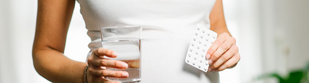 Mulher com copo d'água e comprimidos
